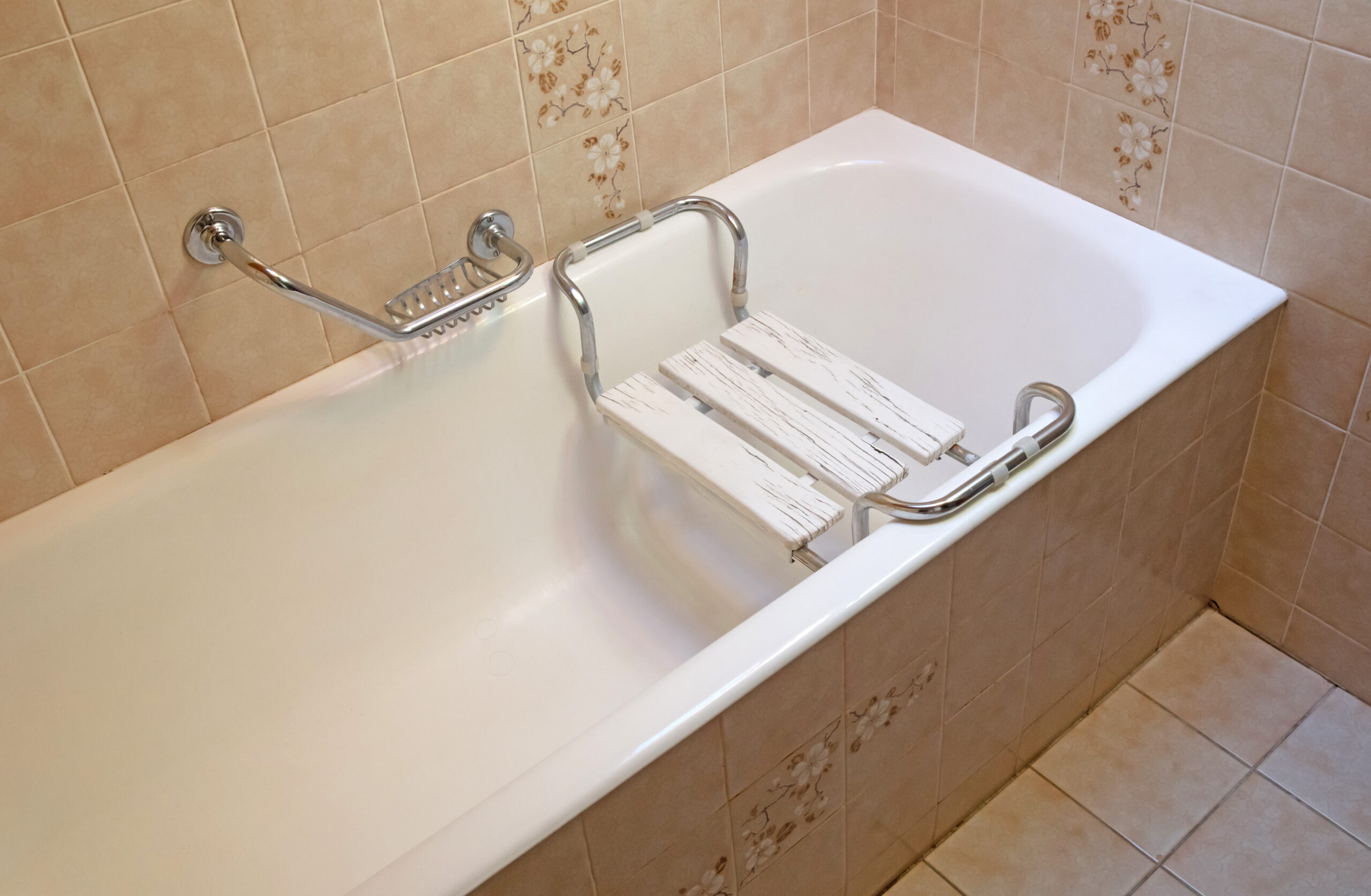 Vasca da bagno equipaggiata con sedile e maniglioni per l'assistenza a persone con disabilità.