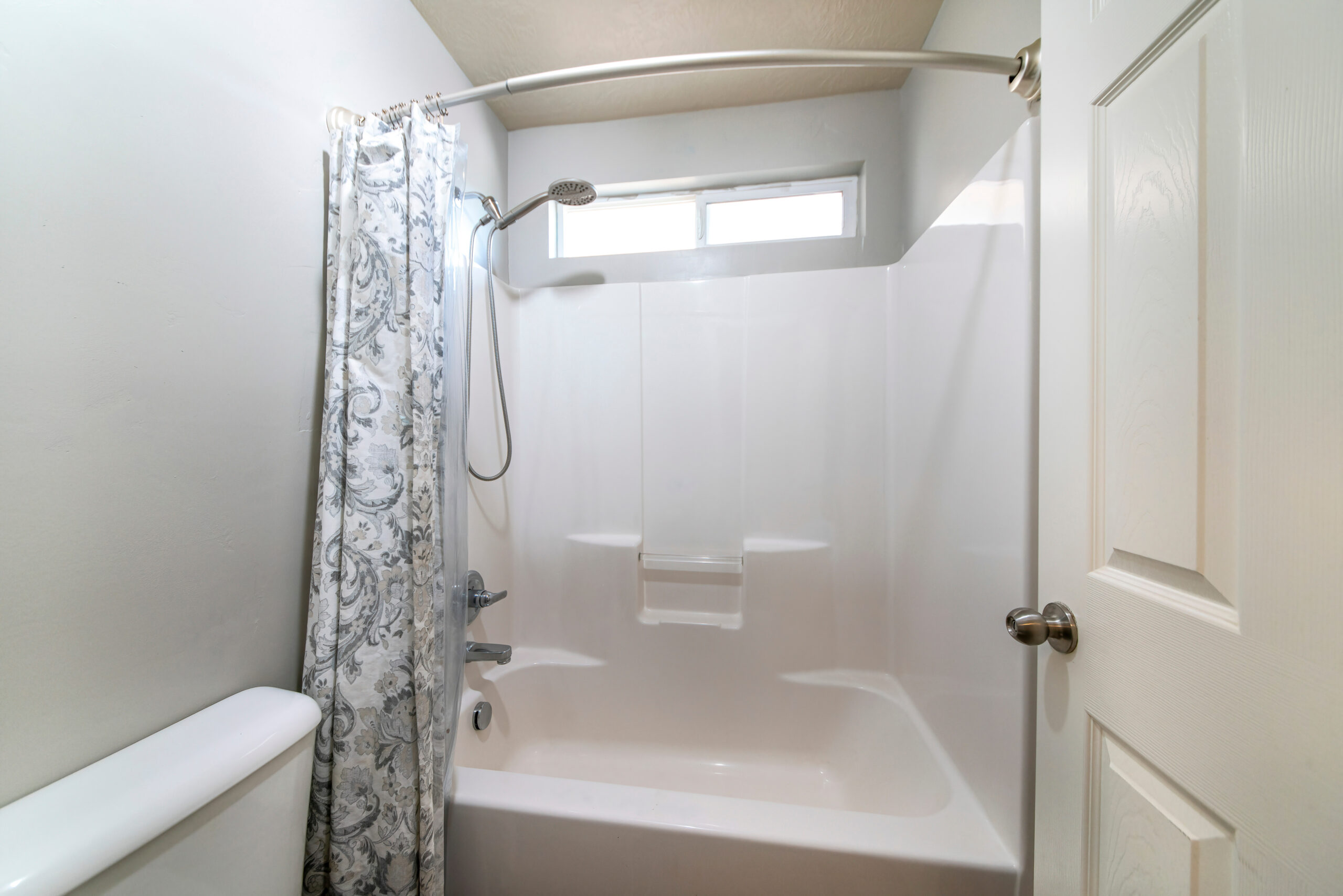 Un bagno con vasca e doccia, tenda floreale, che evidenzia una scelta comune nella ristrutturazione bagno da vasca a doccia per modernizzare lo spazio e migliorarne la funzionalità.